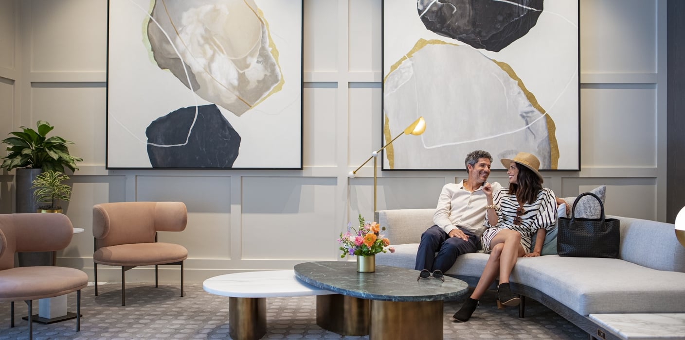 Couple sitting at Clio's Hotel lounge; Man and woman sitting at a gray couch at a Clio's Hotel lounge.