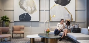 Couple sitting at Clio's Hotel lounge; Man and woman sitting at a gray couch at a Clio's Hotel lounge.