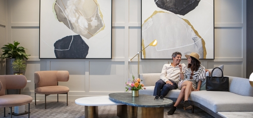 Couple sitting at Clio's Hotel lounge; Man and woman sitting at a gray couch at a Clio's Hotel lounge.