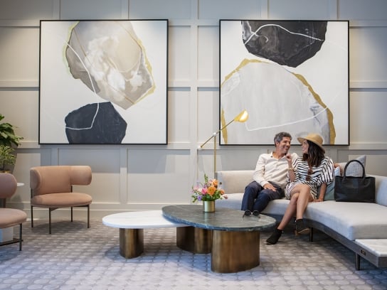 Couple sitting at Clio's Hotel lounge; Man and woman sitting at a gray couch at a Clio's Hotel lounge.