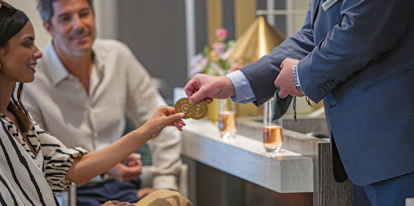 Event/meeting at Hotel Clio; A Man and woman at a meeting sitting and talking to a standing man wearing a blue suit.