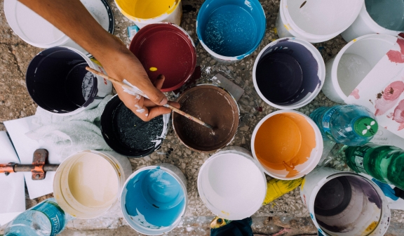 close up view of a painter with jugs of different color paints