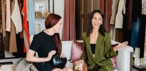 two women sitting on a chair laughing