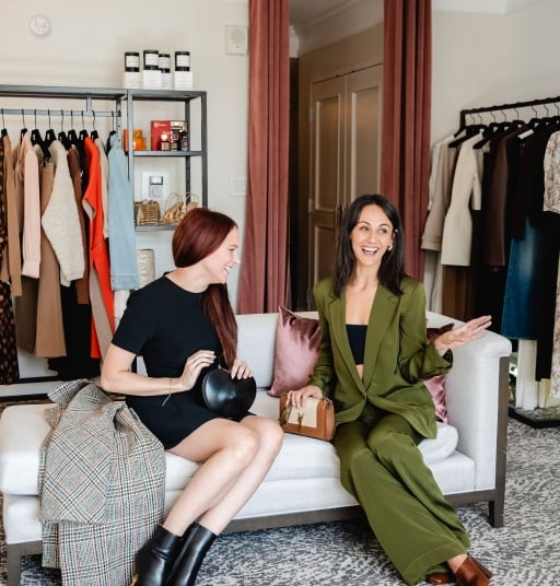 two women sitting on a chair laughing