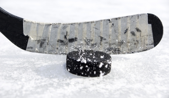 close up of a hockey stick and a puck on the ice