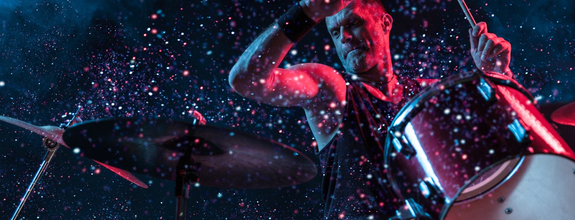 a drummer playing his drums and sparkles in the background