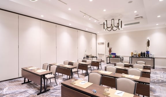 Meeting room at Hotel Clio with multiple rows of desks and chairs ready for a business meeting