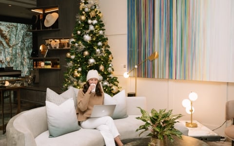 a woman enjoying a drink while sitting in a common area inside Hotel Clio